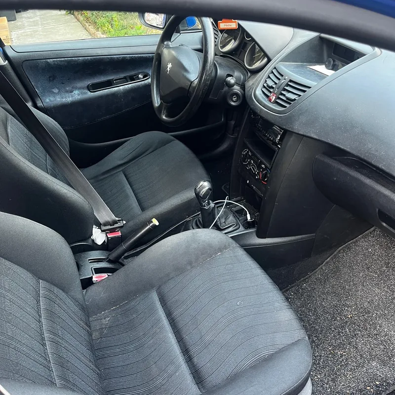 Peugeot 207 avant nettoyage : miettes et poussière sur les tapis de sol et les sièges