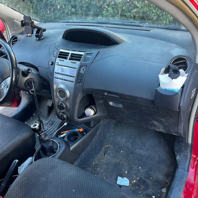 Toyota Yaris avant nettoyage : tableau de bord poussiéreux, tapis de sol pleins de débris